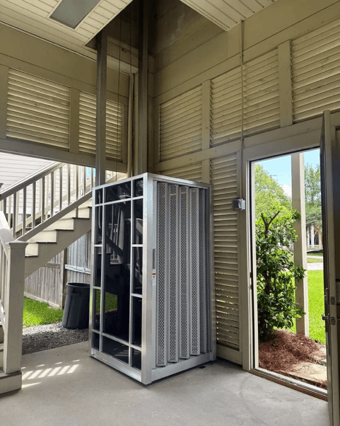 A lakeside great room at sunset with a cargo lift serving the mezzanine level.